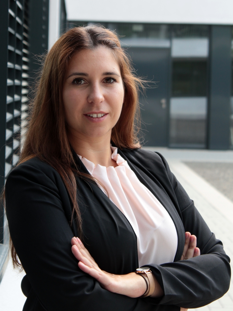 Julia Bausch, holding her arms crossed and looking friendly into the camera